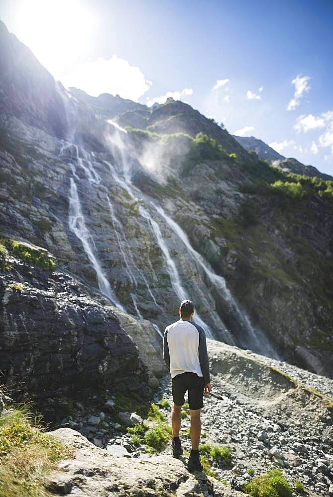 Russia, Karachay-Cherkessia, Arkhyz, Man standing near Sofiyskiye Vodopady waterfall in Caucasus Mountains