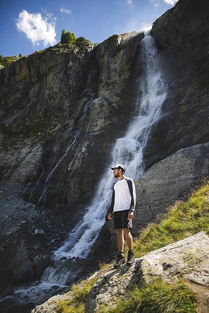 Russia, Karachay-Cherkessia, Arkhyz, Man standing near Sofiyskiye Vodopady waterfall in Caucasus Mountains