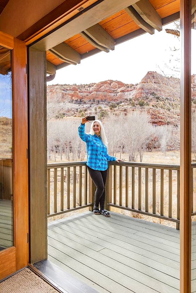 USA, Utah, Escalante, Woman on deck of home in canyon in Grand Staircase-Escalante National Monument