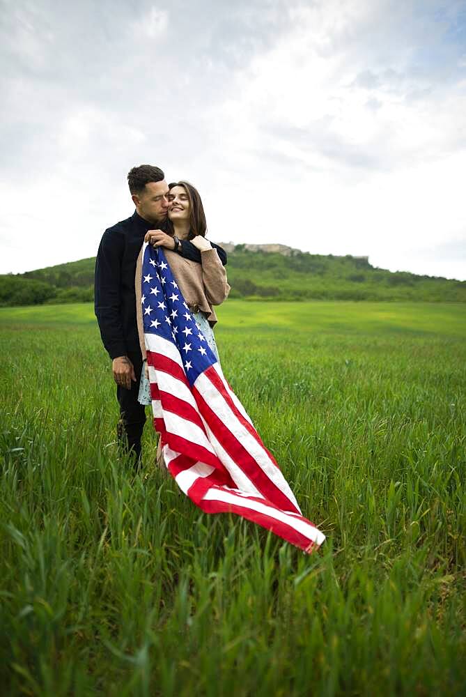 Young couple with American flag in wheat field