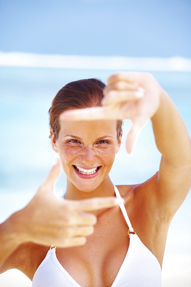 Portrait of woman looking through finger frame