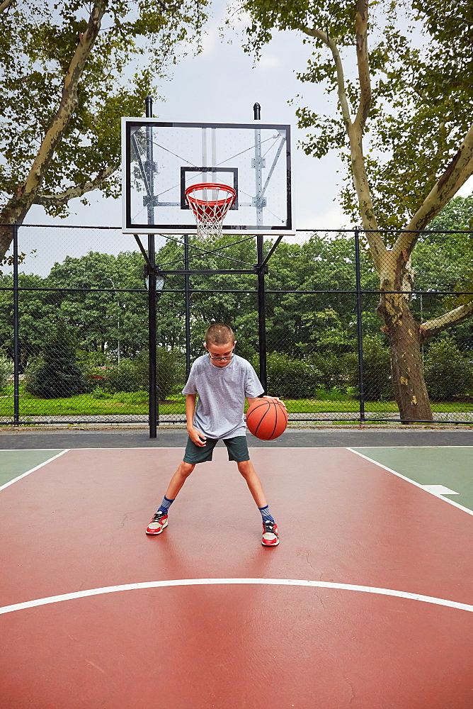 Boy (8-9) playing basketball in park