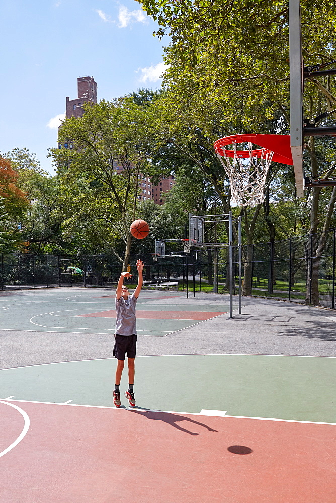 Boy (8-9) playing basketball in park