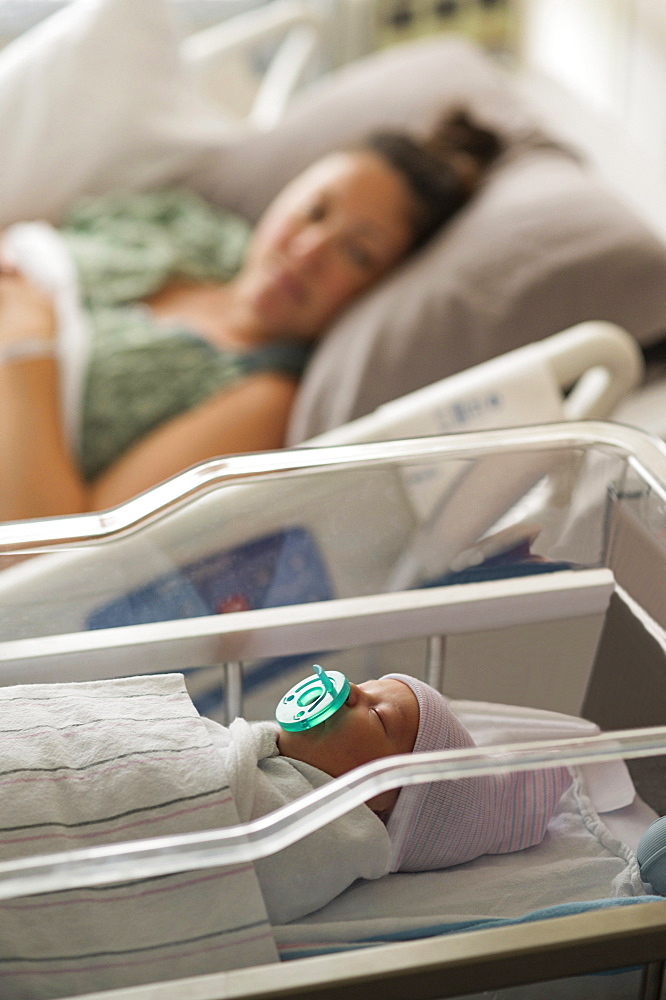 Mother lying with newborn baby girl (0-1 months) in hospital