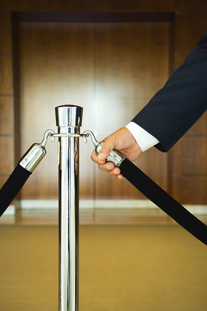 Man holding velvet rope, close up