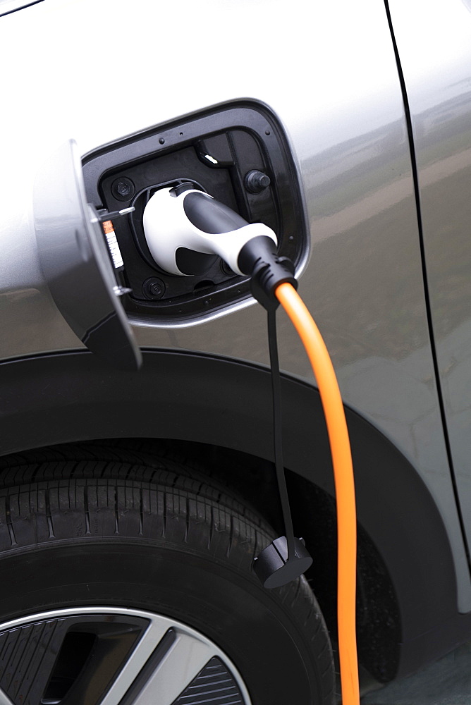 Close-up of electric car being charged with plug-in power cord