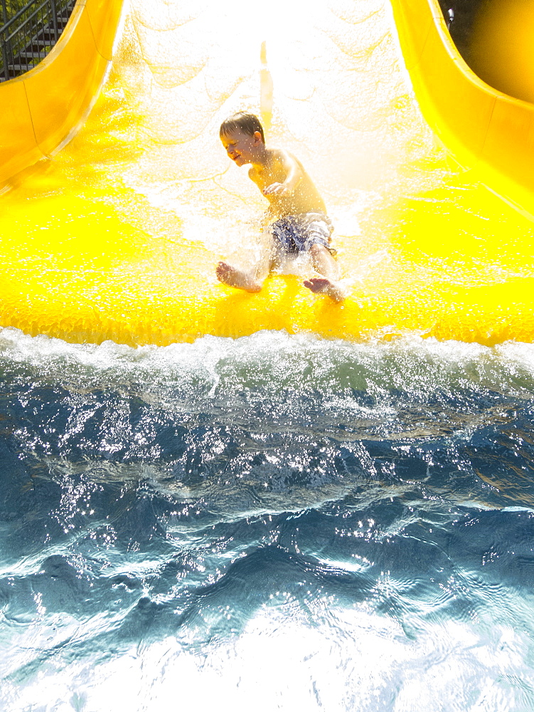 Boy (6-7) having fun on water slide, Germany, Thuringia