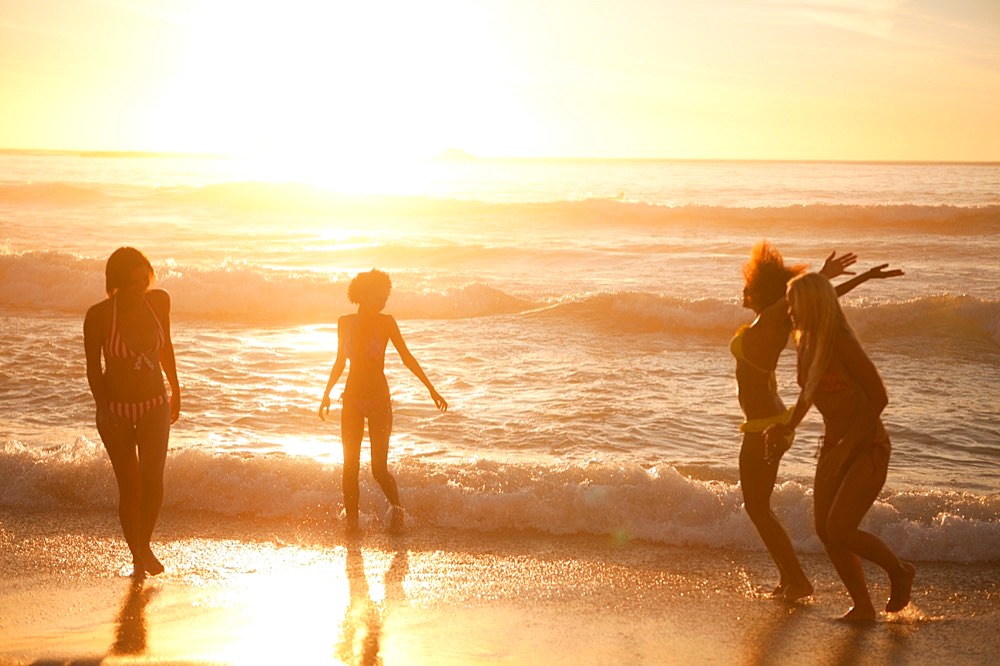 Young happy women playing in front of the ocean