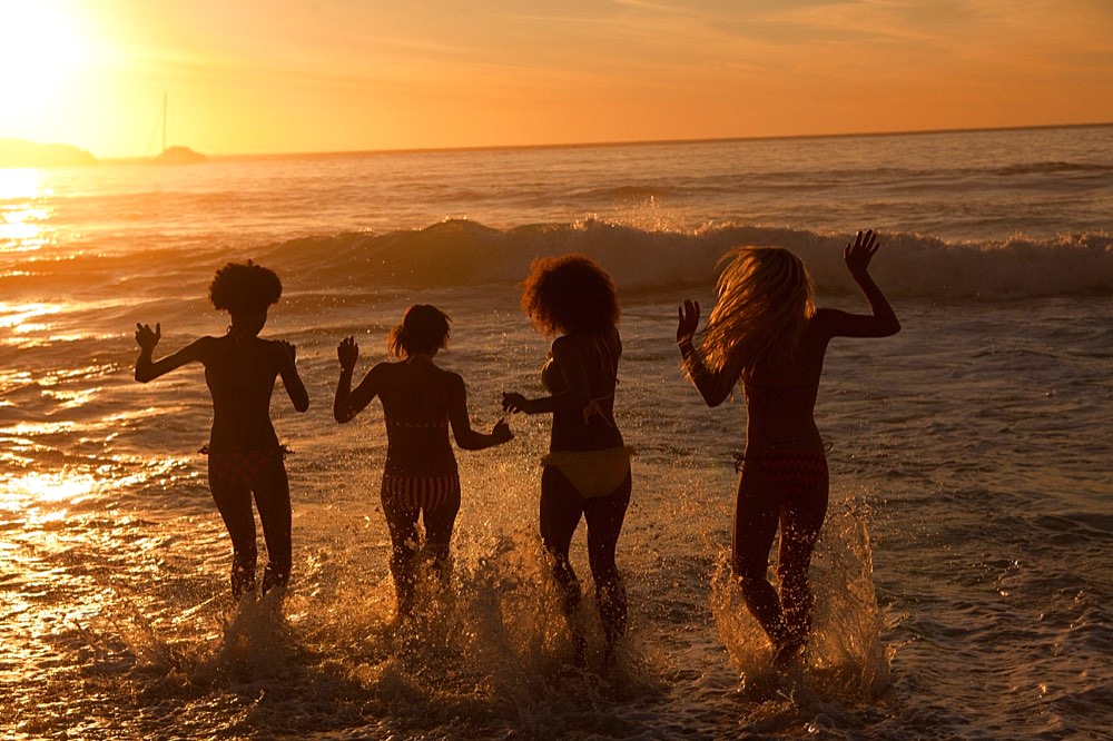 Four young women walking in the water together