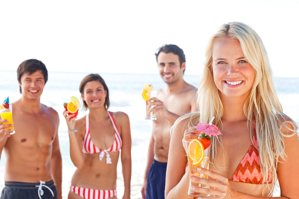 Two couples on the beach enjoying cocktails