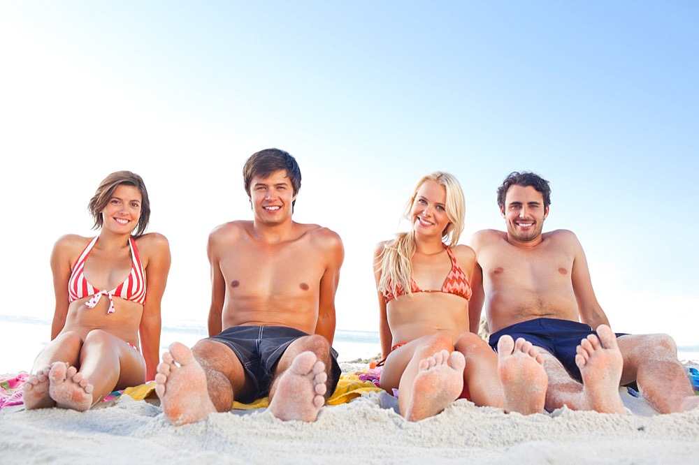 Four friends sitting next to each other while sunbathing