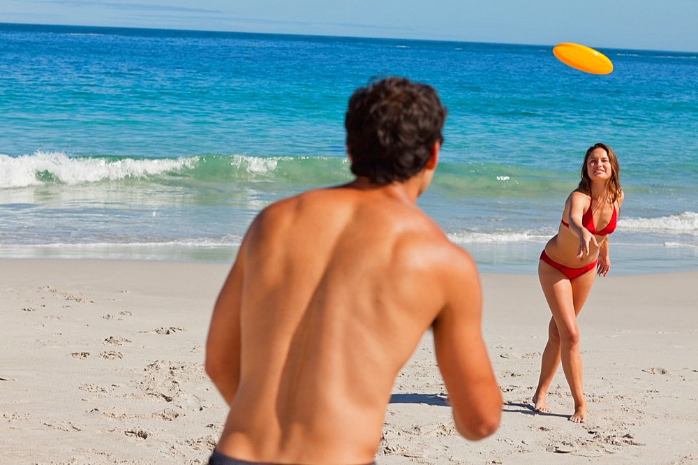 Attractive couple playing with a Frisbee on the beach