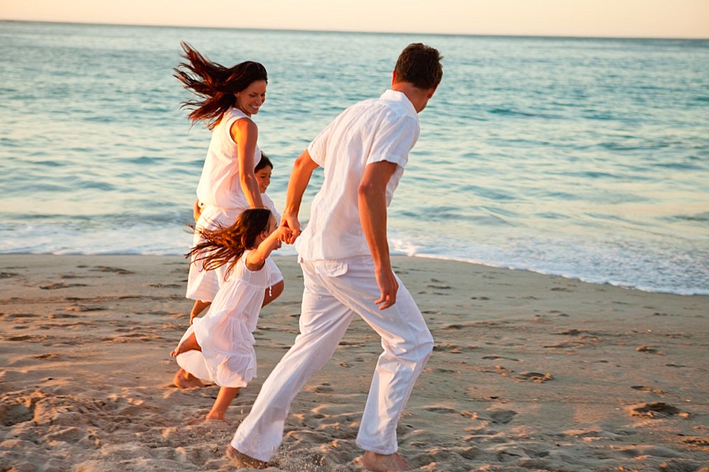 Family holding hands as they walk on the beach