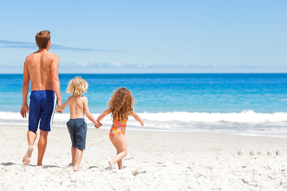 Father walking with his children on the beach