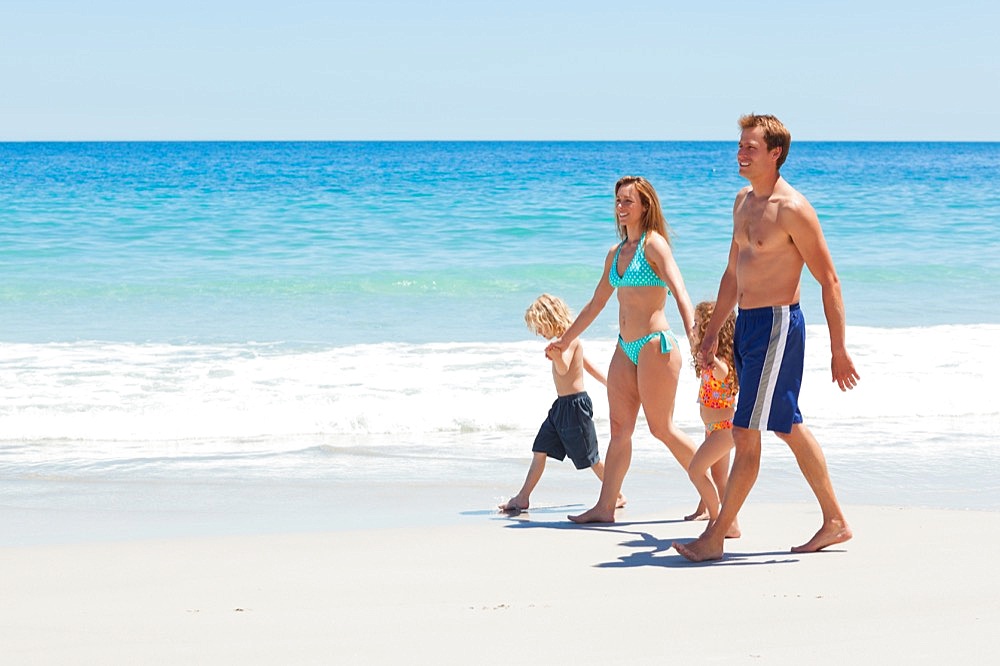Side view of family walking together along the beach