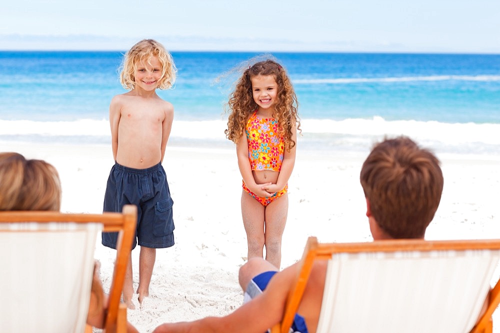 Children standing in front of their parents on the beach