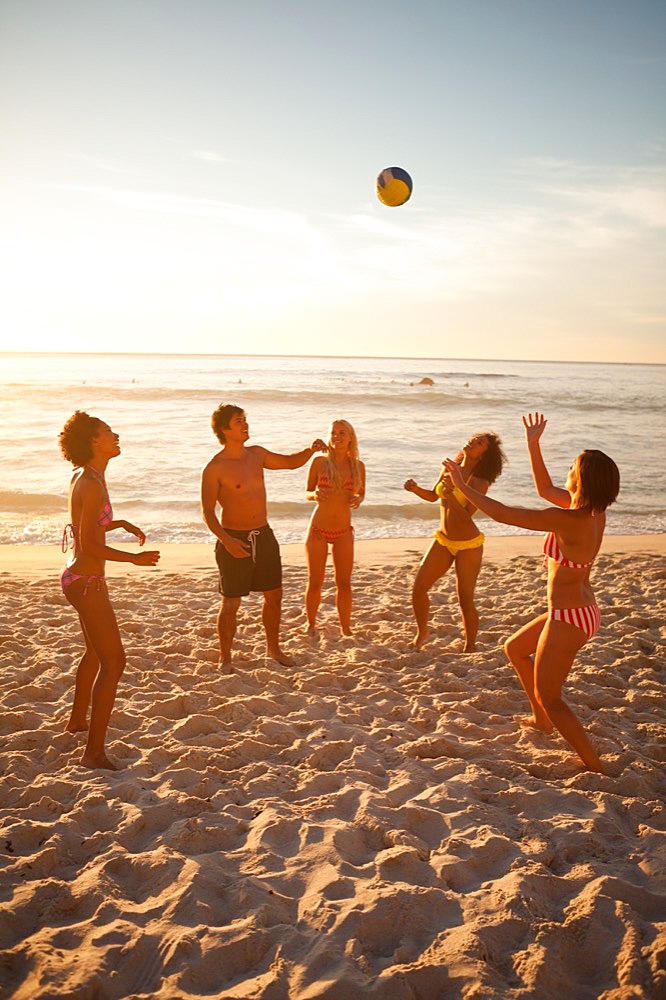 Young people in swimsuits playing with a beach ball