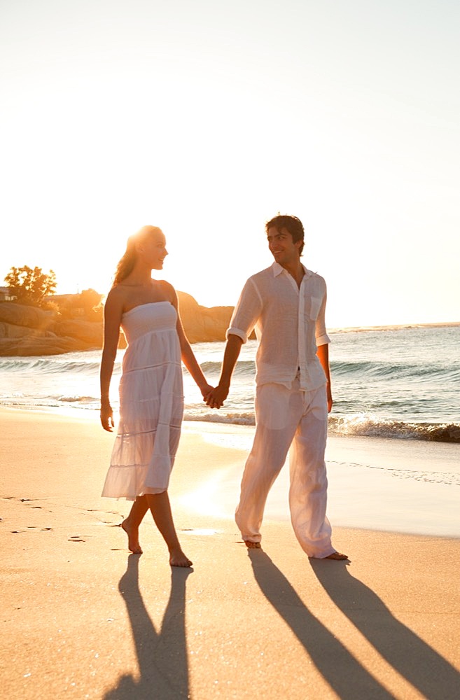 Young couple walking on the beach at sunset