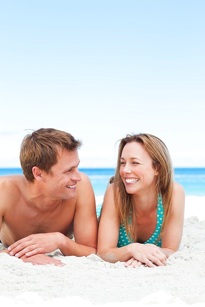 Happy couple lying on the beach