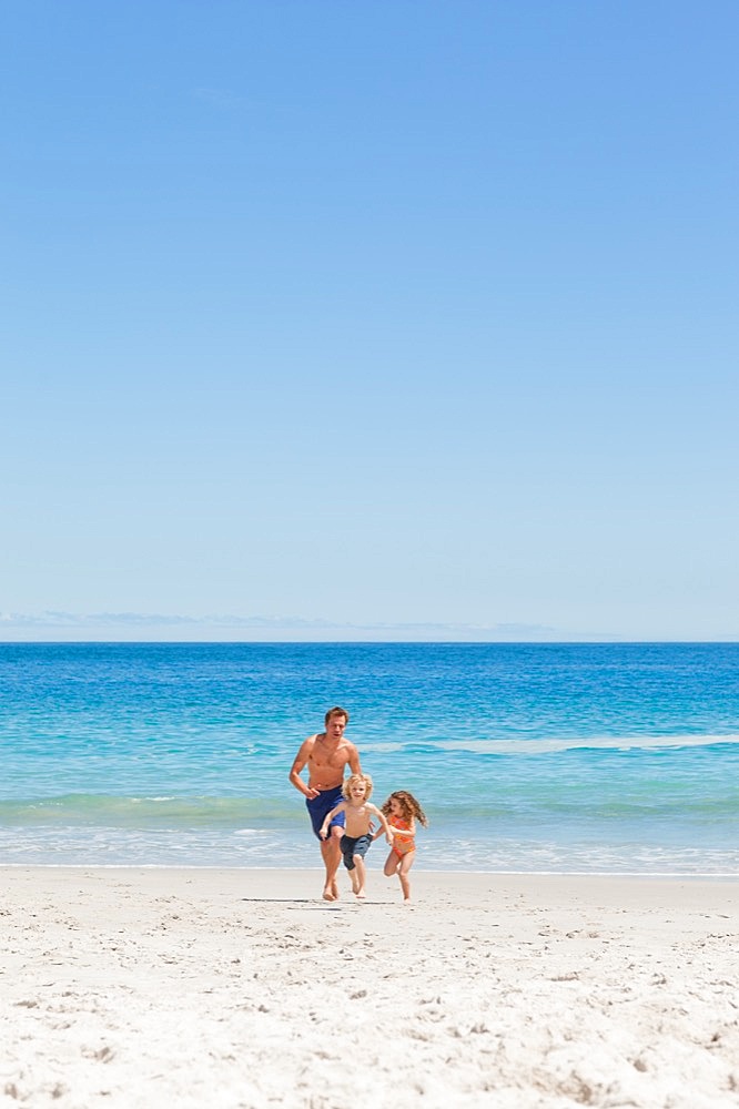 Father running with his children on the beach