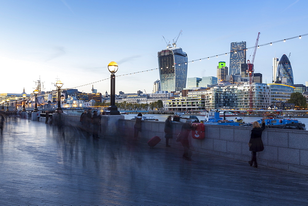 Tourists walking along the South Embankment of the River Thames at London Bridge, with the Gherkin and 'The Walkie-Talkie' amongst the City of London skyline, London, England, United Kingdom, Europe