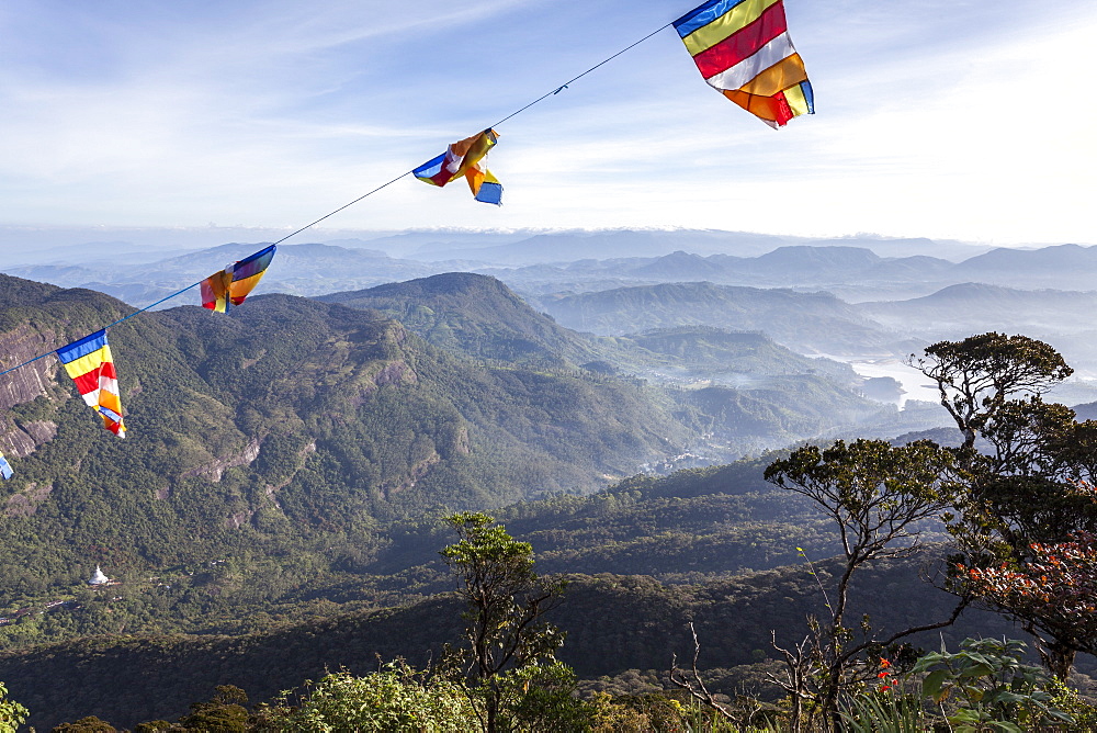 Buddhist flags framing the view down into the Dalhousie and the Hill Country beyond at sunrise from Adam's Peak (Sri Pada), Sri Lanka, Asia 