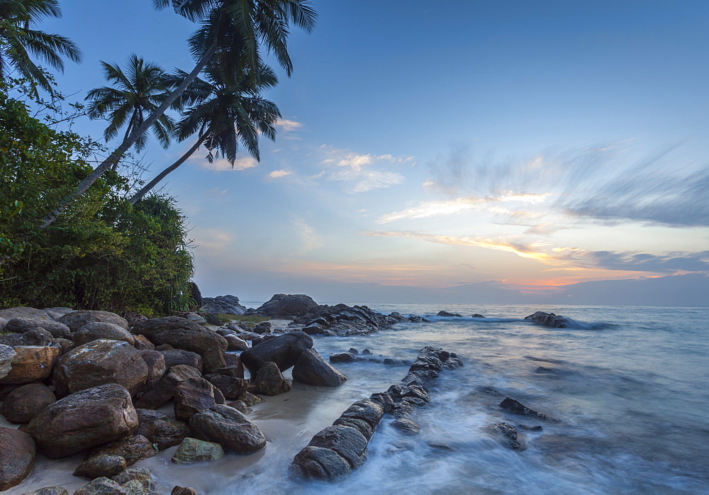 Sunrise at a secluded lagoon with rocks and palm trees framing the view, Tangalle, Sri Lanka, Indian Ocean, Asia 