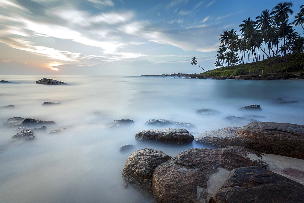 Sunrise at a secluded lagoon with rocks and palm trees framing the view, Tangalle, Sri Lanka, Indian Ocean, Asia 