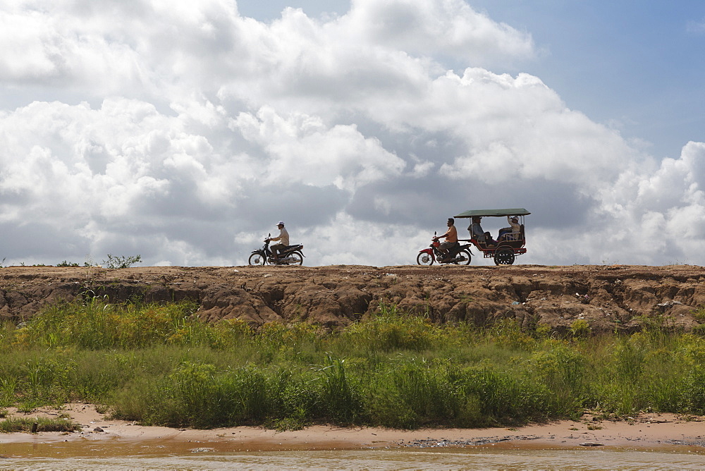 A motorbike being followed by a moto-rickshaw along the banks of the Tonle Sap Lake, Cambodia, Indochina, Southeast Asia, Asia