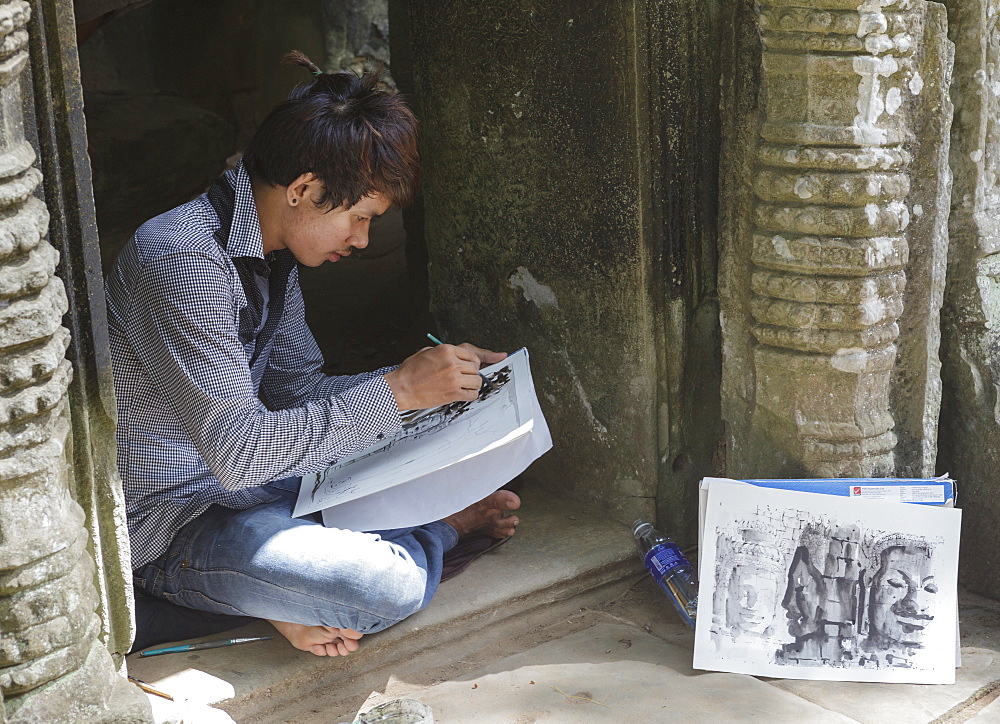 A boy sketches the smiling faces, Ta Prohm, Angkor, Cambodia, Indochina, Southeast Asia, Asia