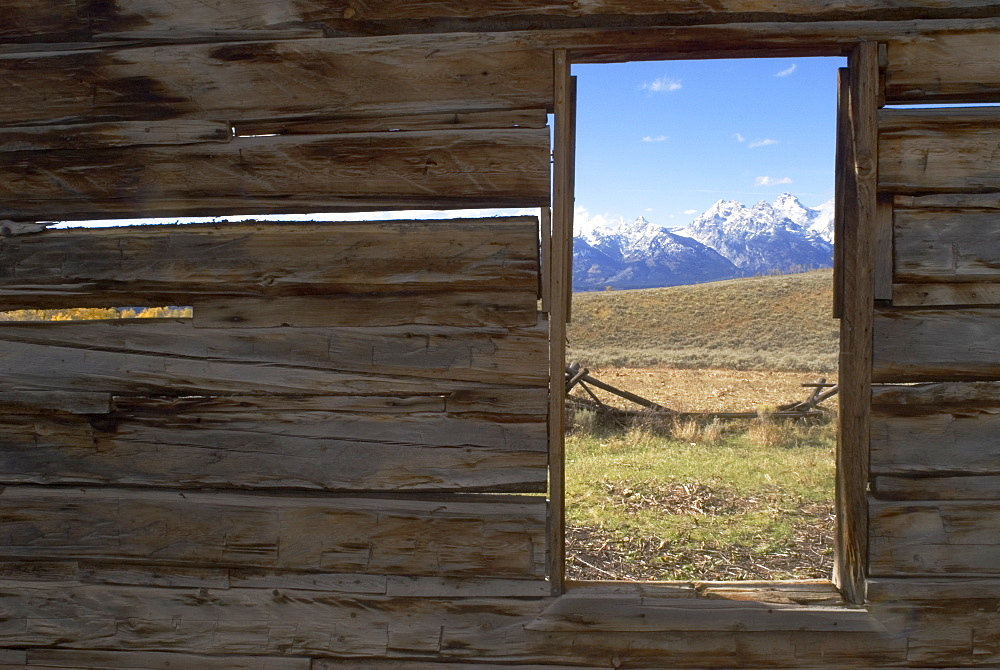 Looking through window of abandoned barn at Teton Mountain range, Wyoming, USA