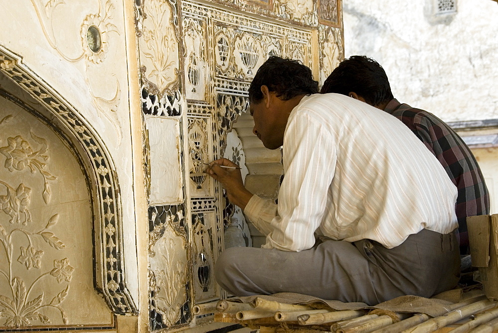 Artisans carrying out repairs on the plasterwork relief at the Amber Fort, Rajasthan, India