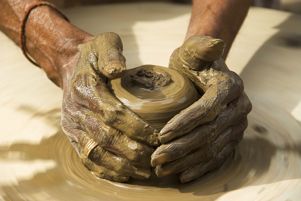 Potter creating clay pots on a manual stone wheel, Udaipur, Rajasthan, India