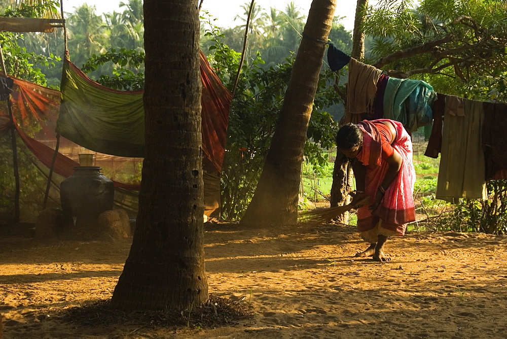 Local woman sweeping the area around the farmhouse, Gokarna, Karnataka, India