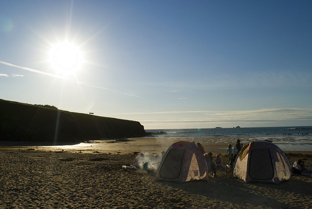 Family having BBQ on beach at sunset, Cornwall, UK