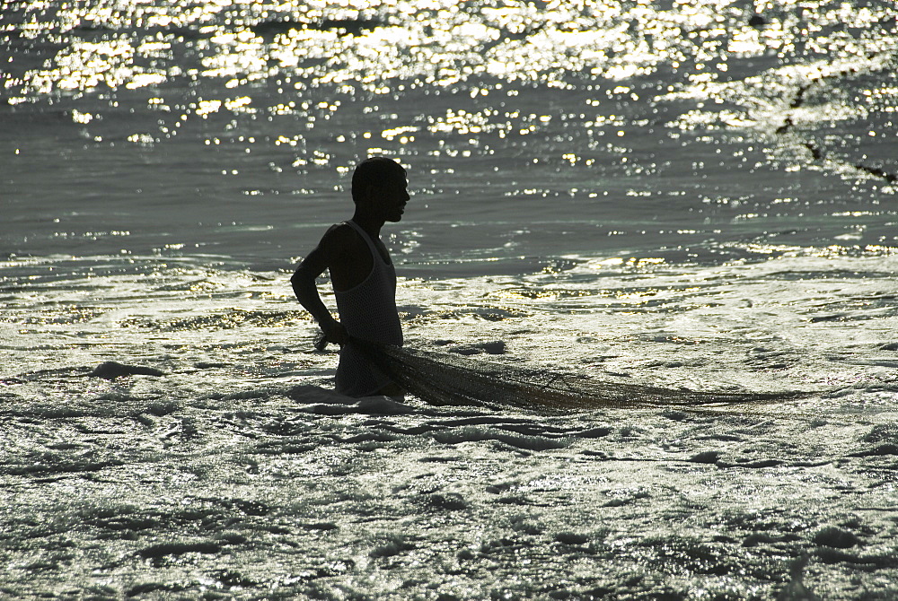 Fisherman standing in the sea ready to pull in the net, Goa, India