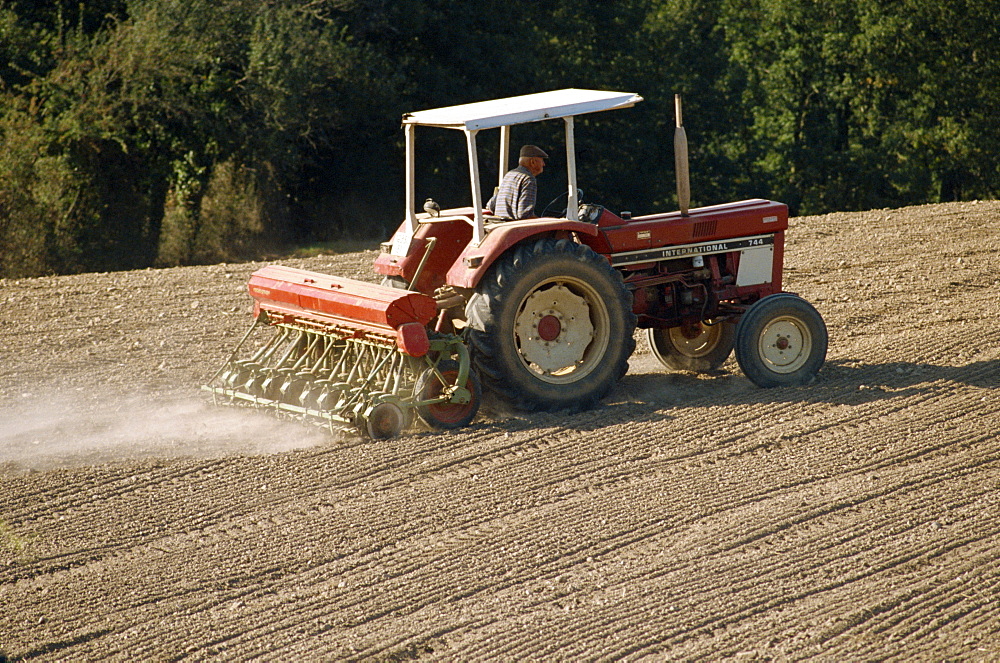 A tractor with a seed drill, drilling rape seed in autumn in the Tarn, France, Europe