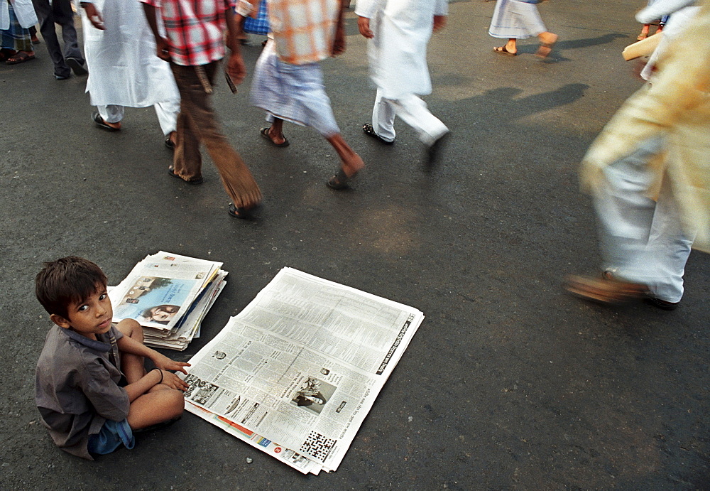 A little boy selling newspapers  on the street of Kolkata, India