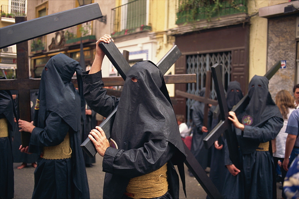 Penitents bearing crosses in procession, Holy Week (Semana Santa), Seville, Andalucia, Sapin, Europe