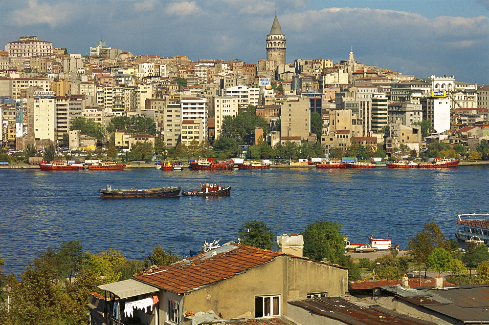 Boats on the Golden Horn, with apartment blocks, commercial buildings and the Galata Tower beyond in Istanbul, Turkey, Europe