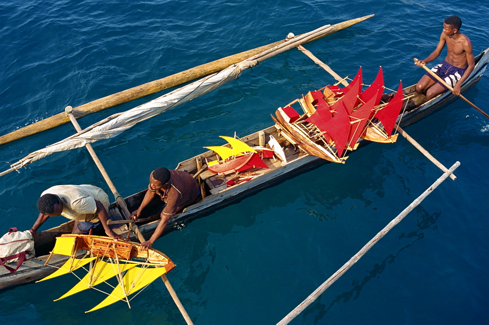 Local men transport model boats by canoe to market, Nosy Be Island, Madagascar, Africa