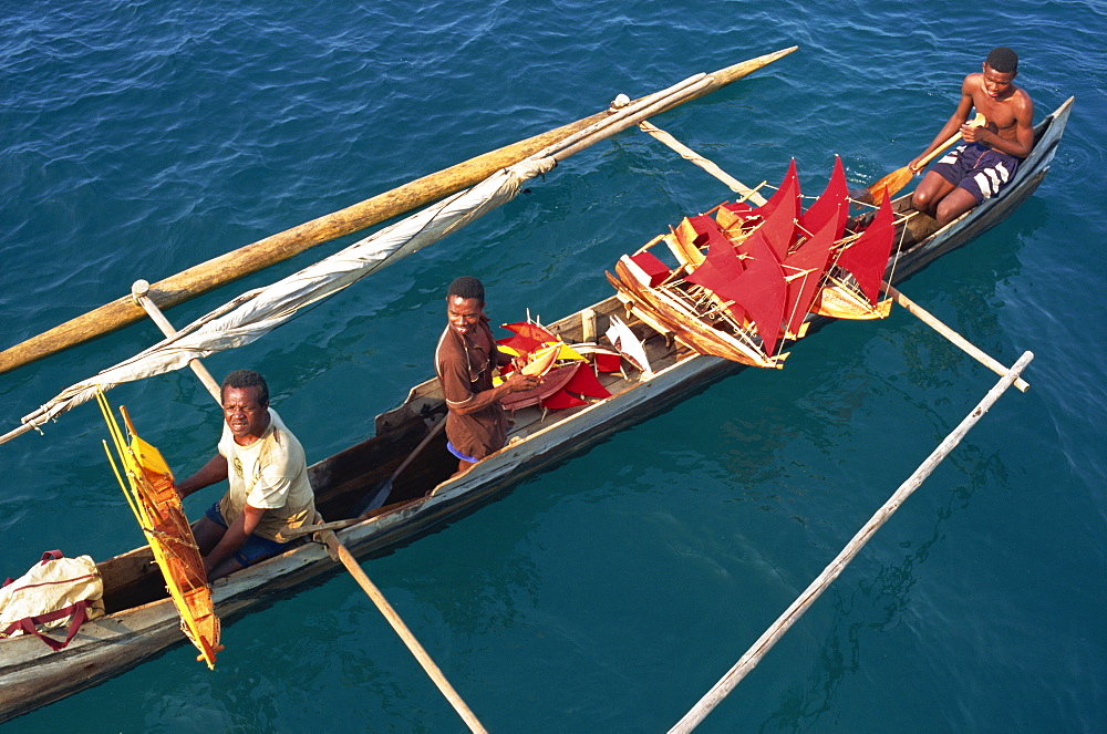 Men in outrigger canoes selling model boats with red sails, Nosy Be, Madagascar, Africa