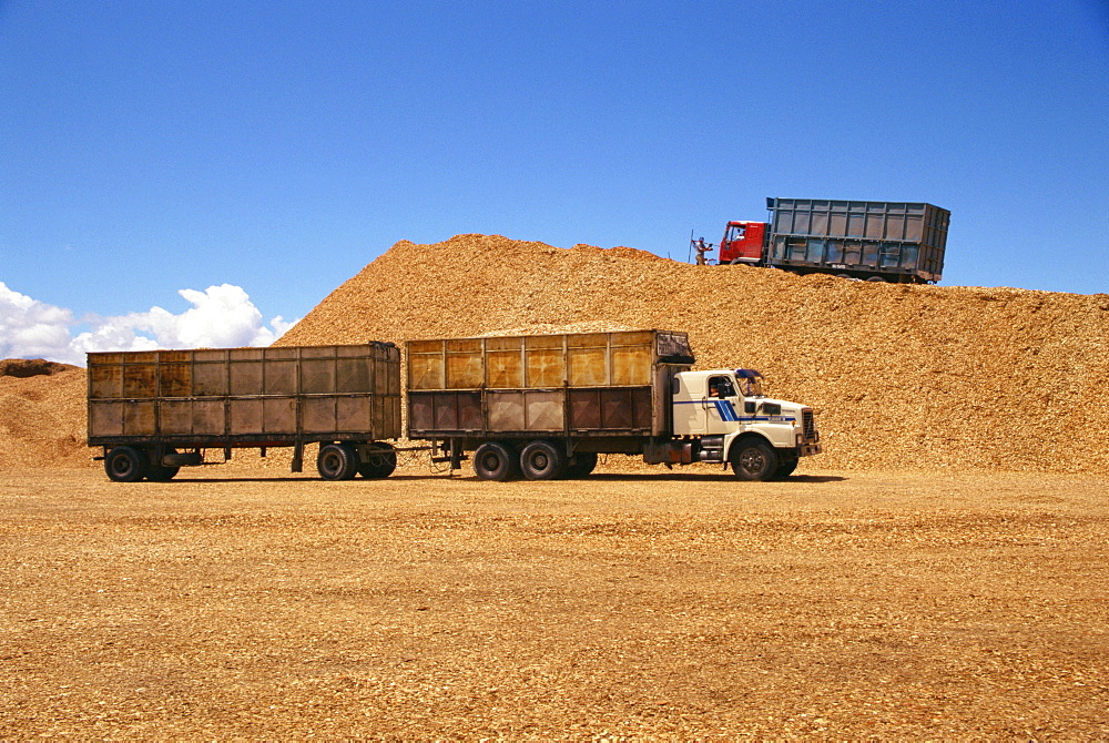 Trucks and trailers at the wood chip stocks at the port awaiting export at Puerto Montt in the Lake District of Chile, South America