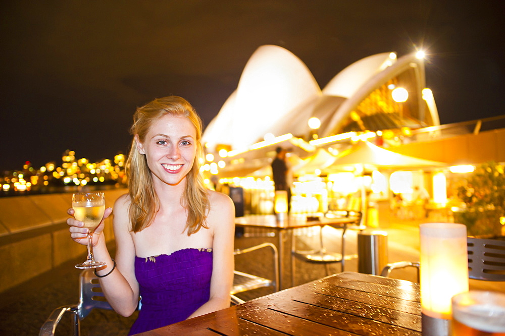 Young woman enjoying Sydney nightlife, having a drink at Opera Bar, Sydney Opera House, Sydney, New South Wales, Australia, Pacific