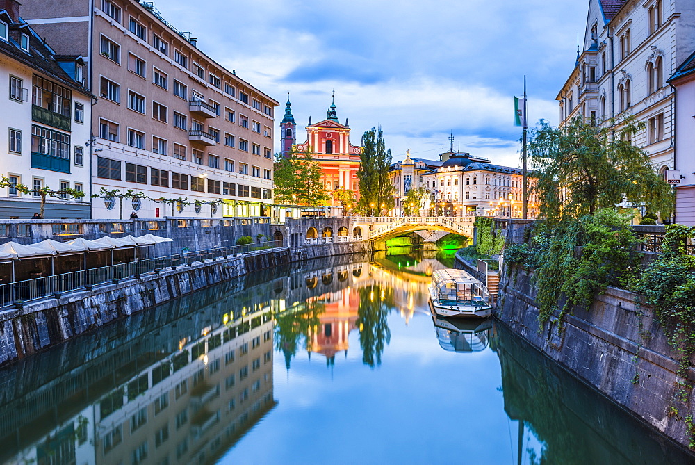 Ljubljana triple bridge and the Franciscan Church of the Annunciation reflected in Ljubljanica River at night, Lubljana, Slovenia, Europe