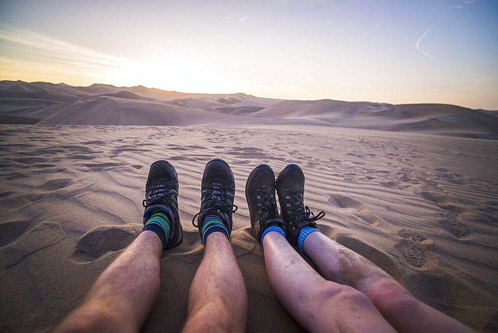 Couple watching the sunset over sand dunes in the desert at Huacachina, Ica Region, Peru, South America