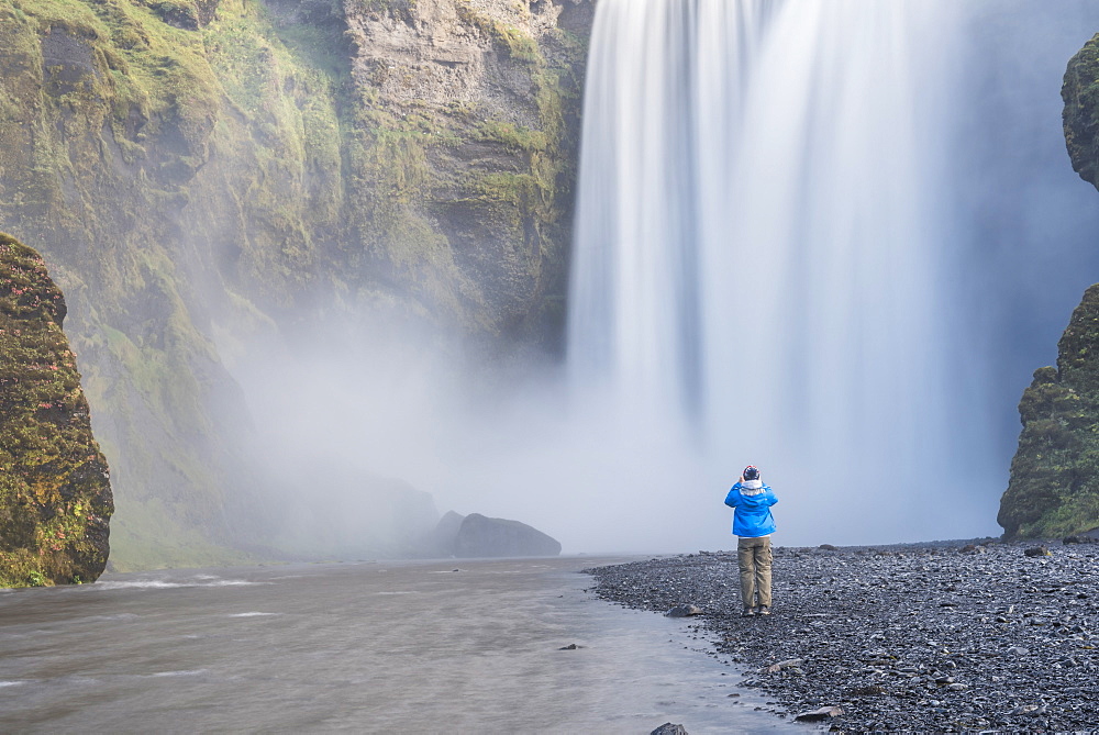 Tourist taking a photo of Skogafoss Waterfall, Skogar, South Region (Sudurland), Iceland, Polar Regions