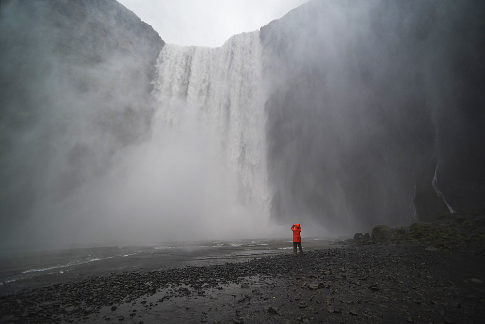 Tourist taking a photo in the spray at Skogafoss Waterfall, Skogar, South Region (Sudurland), Iceland, Polar Regions