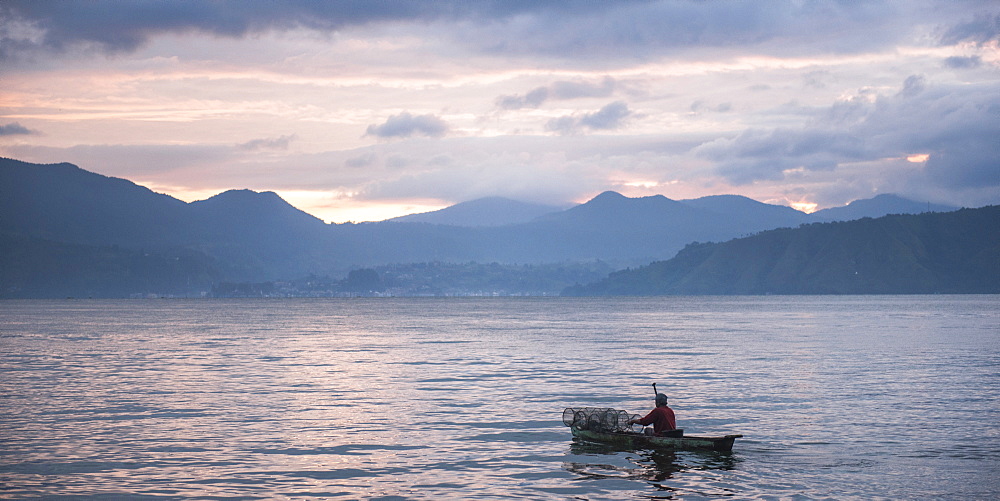 Fisherman in a fishing boat on Lake Toba (Danau Toba) at sunrise, North Sumatra, Indonesia, Southeast Asia, Asia