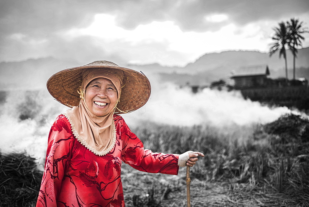 Portrait of a farmer burning crops in rice paddy fields, Bukittinggi, West Sumatra, Indonesia, Southeast Asia, Asia